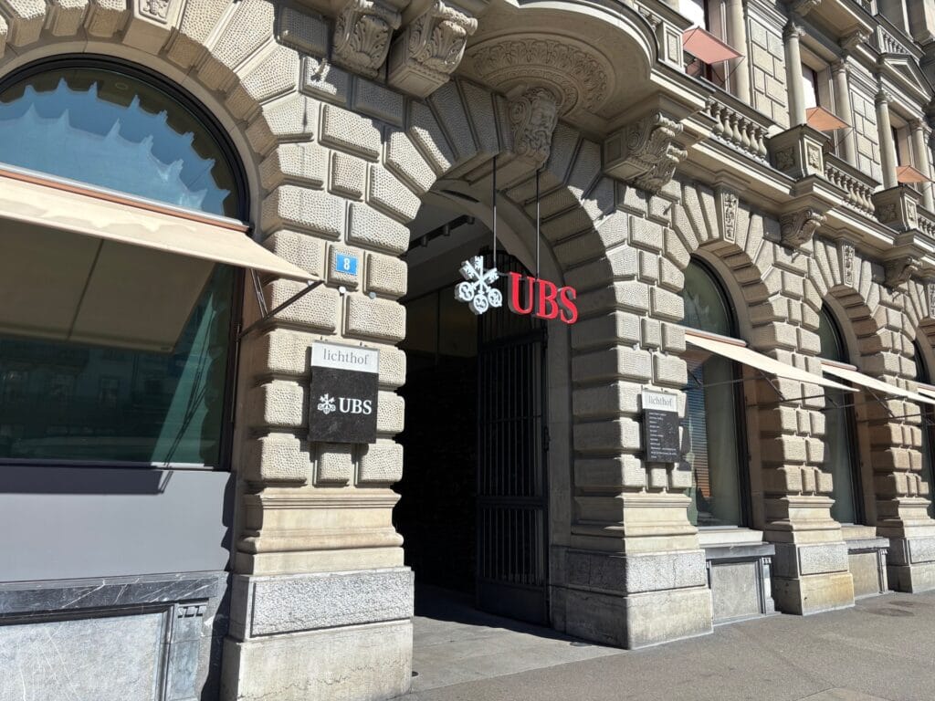 The historic stone exterior and entrance of a UBS branch in Switzerland, representing the major universal banking tier for US citizens and non-resident HNWIs looking to open a Swiss bank account.
